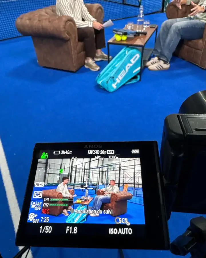 Interview filmée dans un club de padel, vue sur l'écran de la caméra